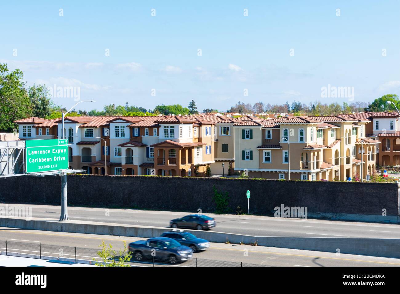 New residential townhomes complex completed next to highway. Concrete noise barrier protects future residents from the motoring sounds of traffic - Su Stock Photo