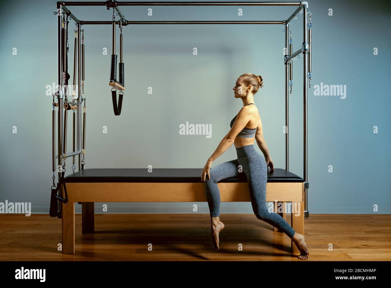 Young woman exercising on pilates reformer bed Stock Photo by