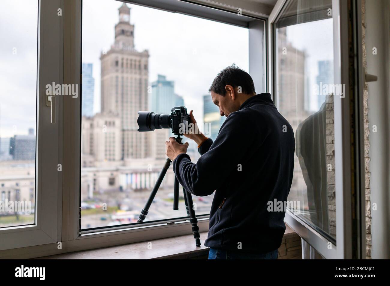 Young man in flat apartment with view of Warsaw, Poland cityscape taking  picture with camera and tripod of famous Palace of Science and Culture  buildi Stock Photo - Alamy