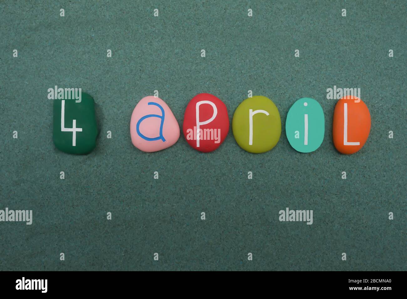 4 April, calendar date composed with colored and carved stones over green sand Stock Photo