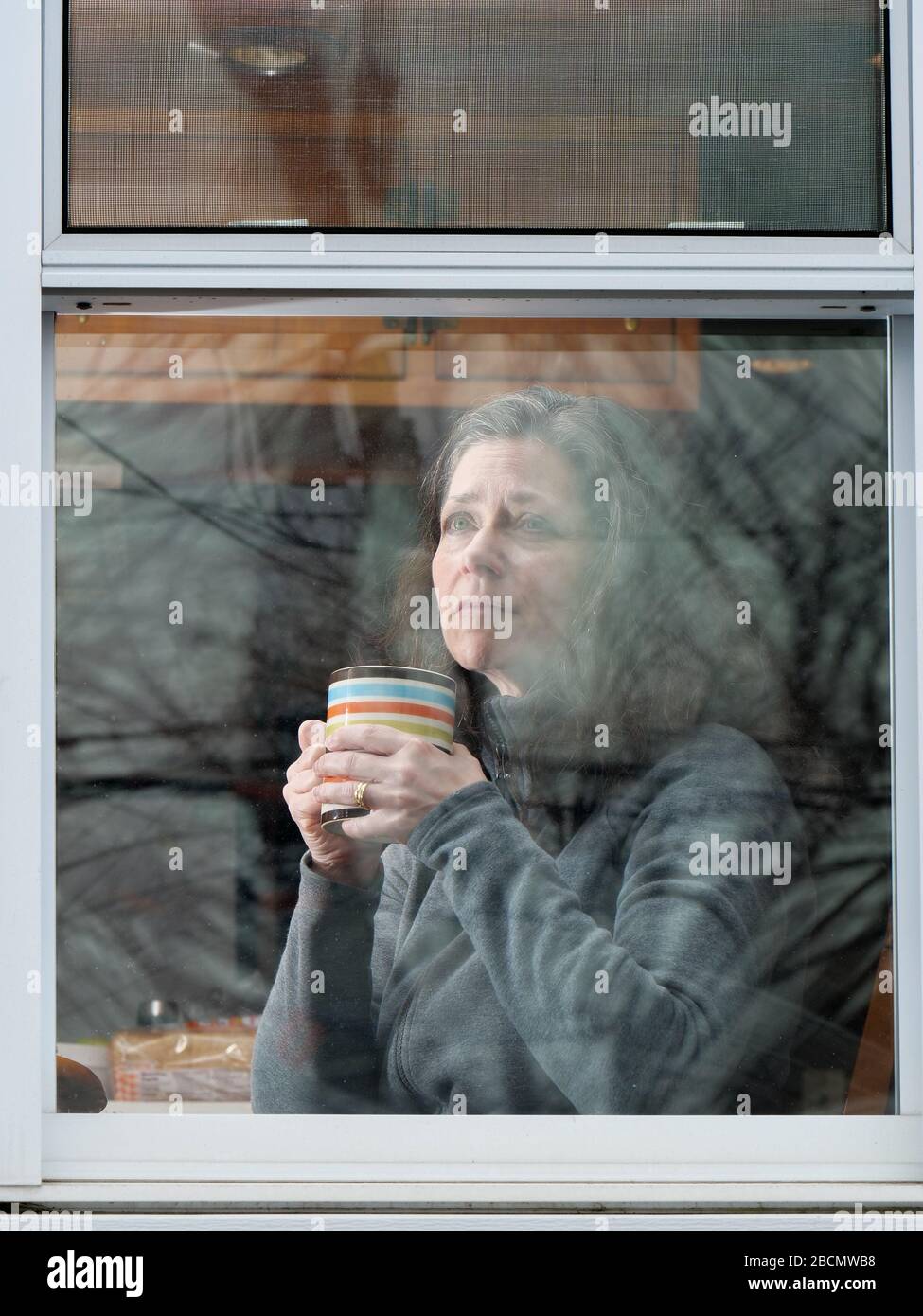 Oak Park, Illinois, USA. 4th April, 2020. A woman looks out her kitchen window during COVID-19 shelter-in-place order. Stock Photo