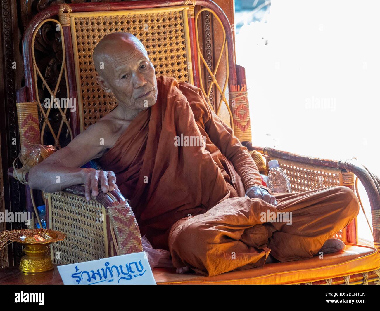Monk, meditating in contemplation crosslegged on a wicker chair with backlighting Stock Photo