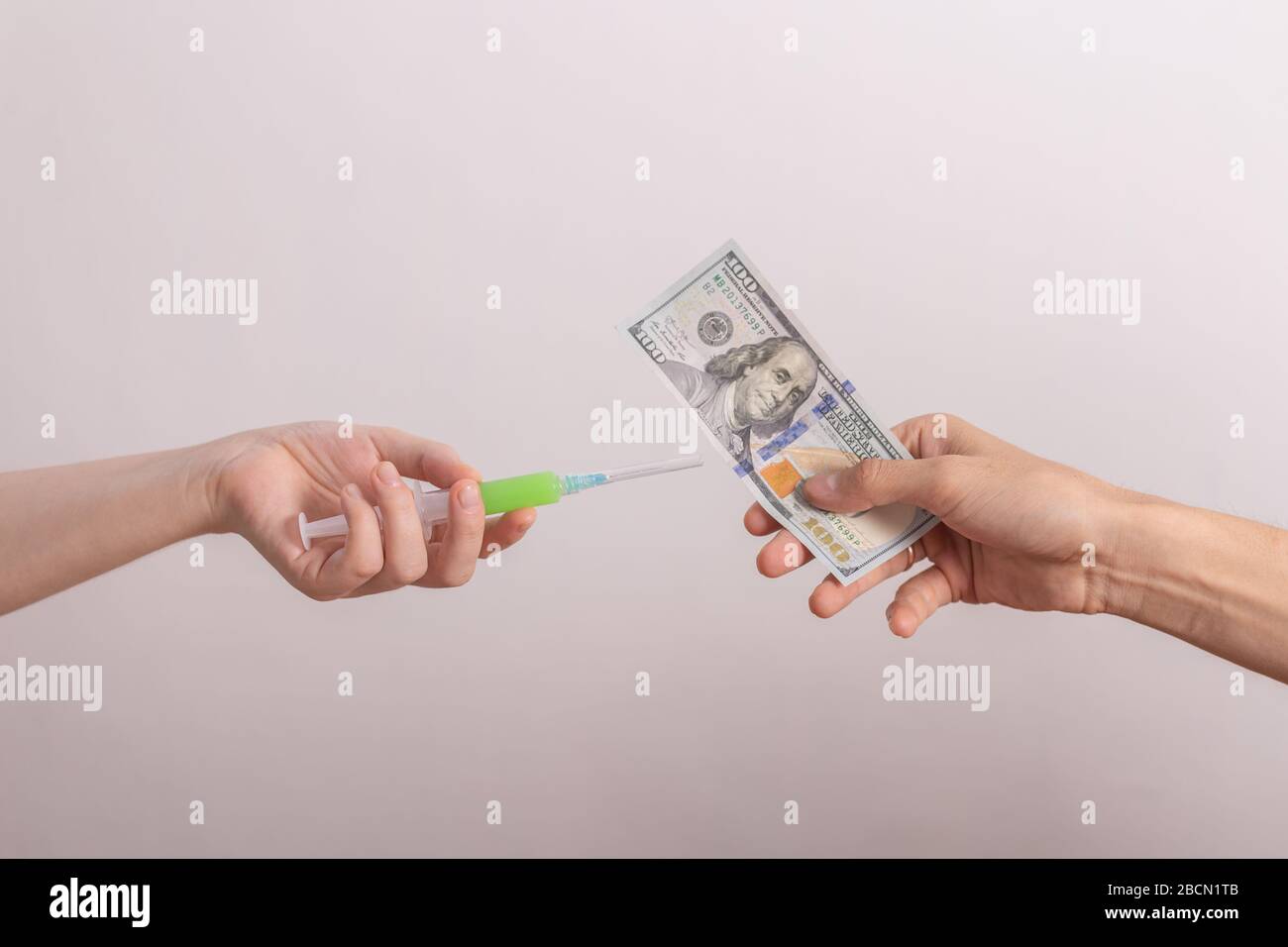 One hand with vaccine and another with money Stock Photo
