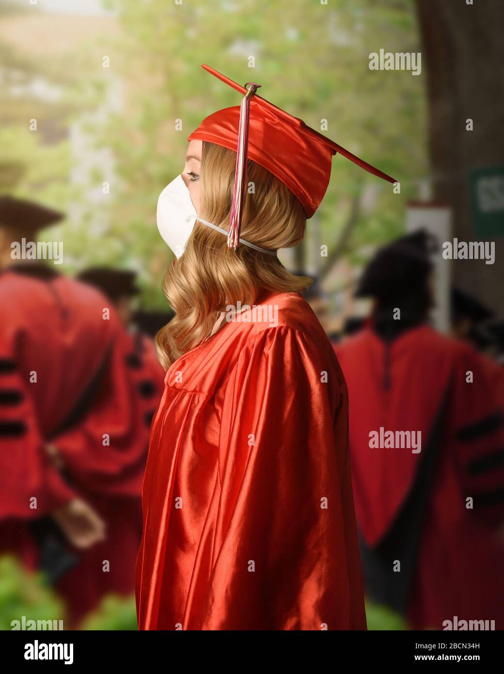 A college graduate is wearing a red robe and cape with a surgerical facial mask for the coronavirus fear on the class of 2020. Stock Photo