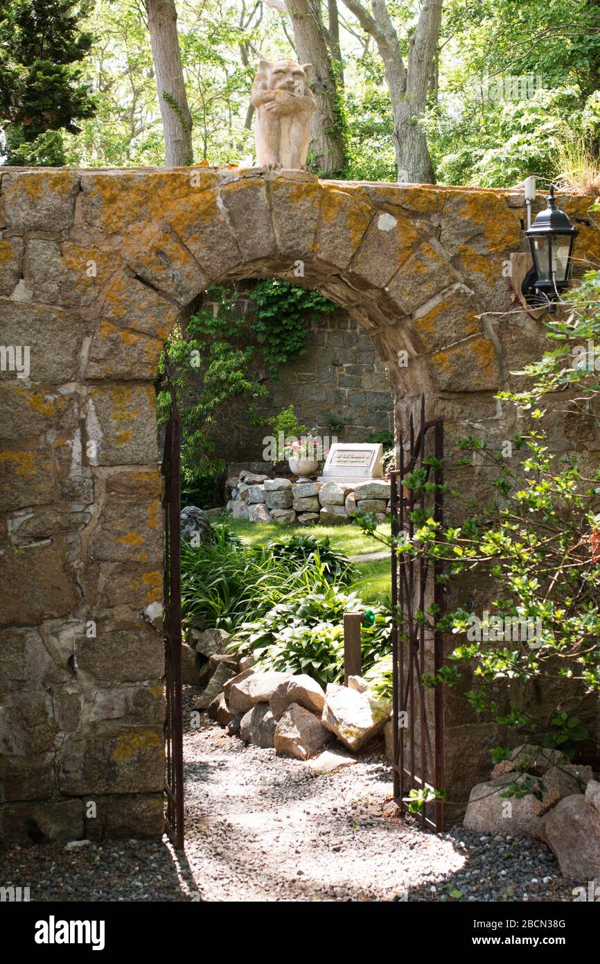 The arched stone gateway (guarded by a gargoyle) leading to the garden