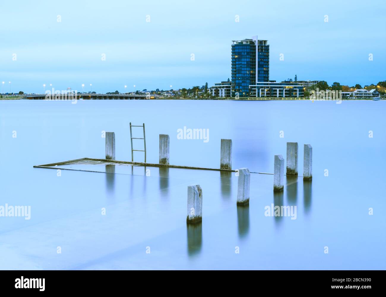 Submerged wooden jetty with ladder in the swan river with Applecross Raffles Hotel in the background Stock Photo