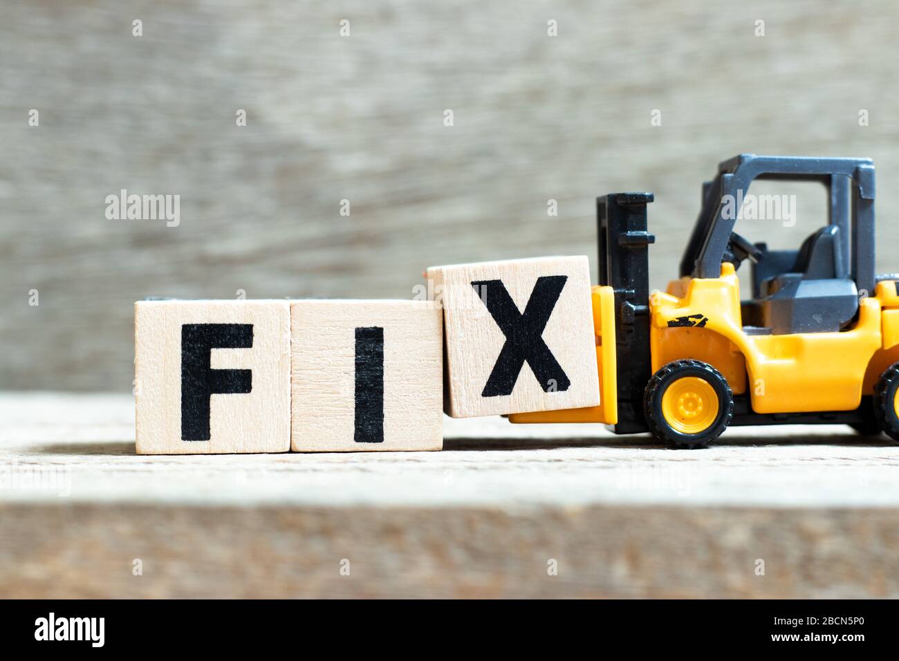 Toy forklift hold letter block x to complete word fix on wood background Stock Photo