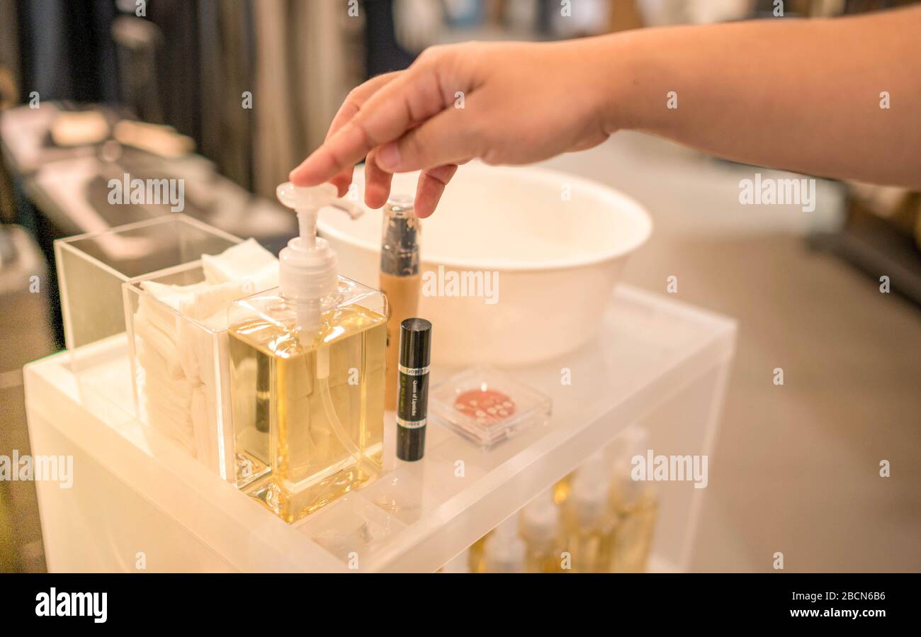 Female hand pressing removal  cleansing oil make up testing bottle teaster for customer at the cosmetic counter in department store. Stock Photo