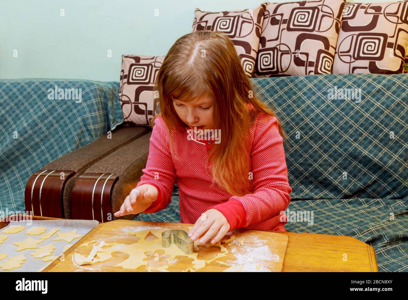Little girl in making with preparing the dough on the table Happy little girl child cooking Stock Photo