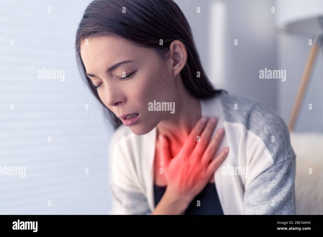 COVID-19 shortness of breath Coronavirus cough breathing problem. Asian woman touching chest in pain with red highlighted area. respiratory symptoms fever, coughing, body aches. Stock Photo