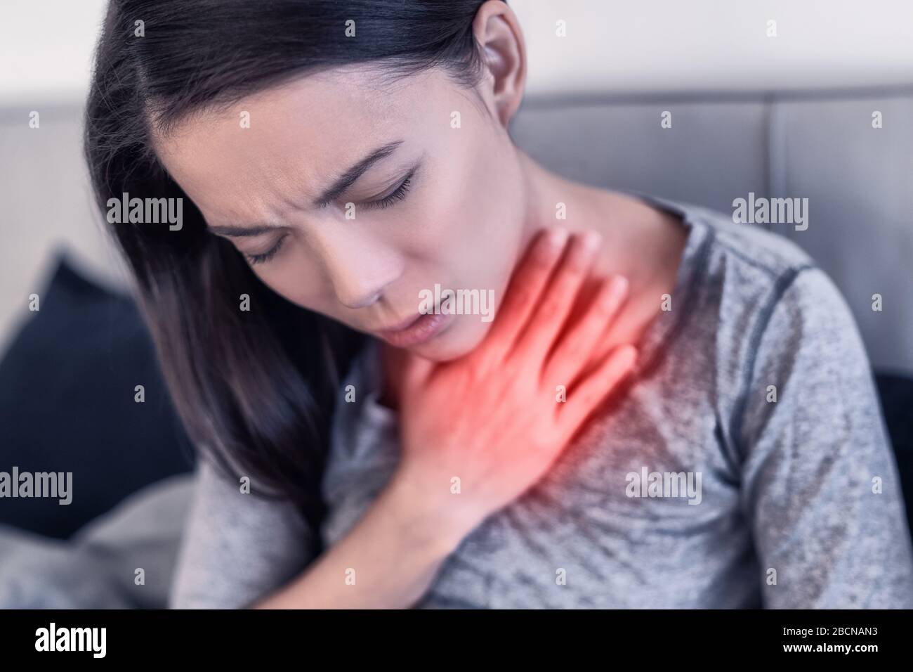 COVID-19 Corona virus symptoms are pneumonia, shortness of breath, fever, body aches or breathing difficulties. Asian woman sick of Coronavirus with red area showing pain. Stock Photo