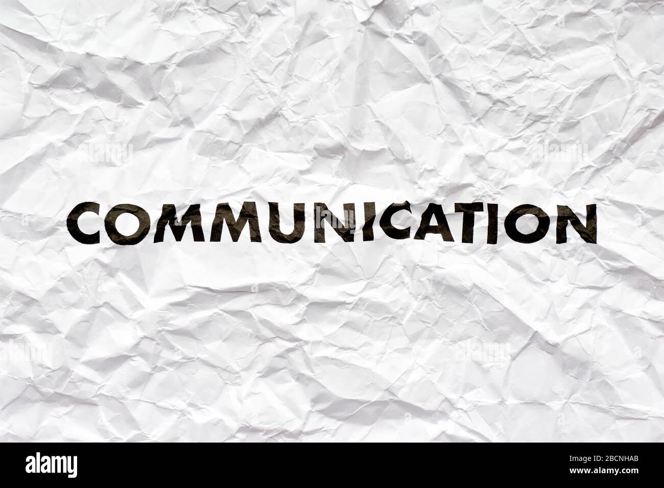 Wrinkled white paper with the word communication printed in black. Concept of bad disrupted communication or miscommunication. Stock Photo