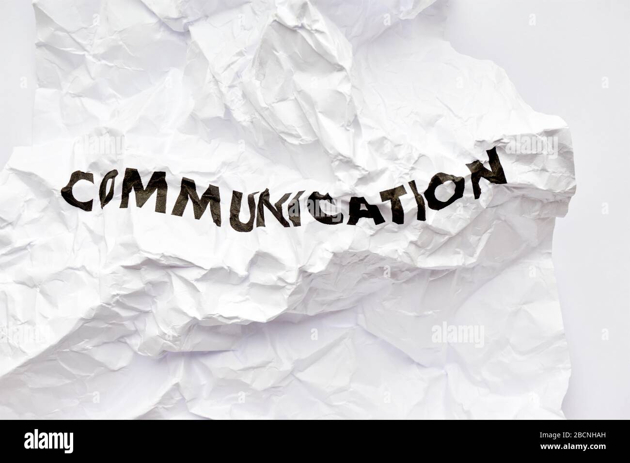 Wrinkled white paper with the word communication printed in black. Concept of bad disrupted communication or miscommunication. Stock Photo