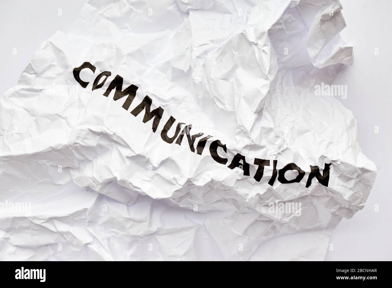 Wrinkled white paper with the word communication printed in black. Concept of bad disrupted communication or miscommunication. Stock Photo