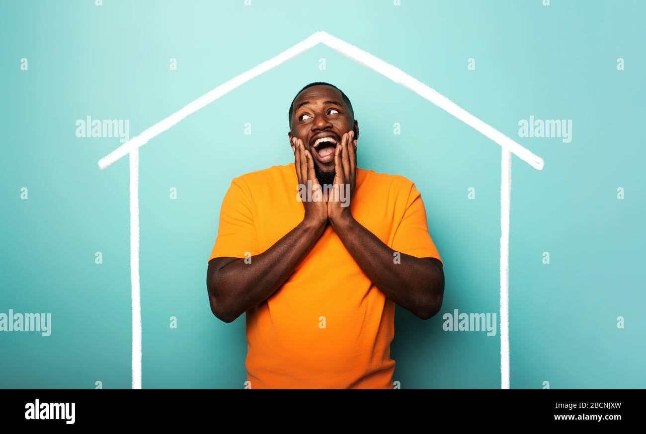 Man is amazed to have bought a house. Cyan background Stock Photo