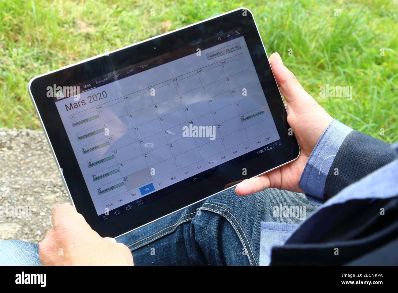 A man is holding a digital tablet displaying a calendar Stock Photo