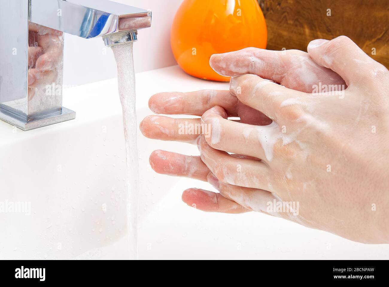 Washing of hands with soap under running water in white sink. close ...