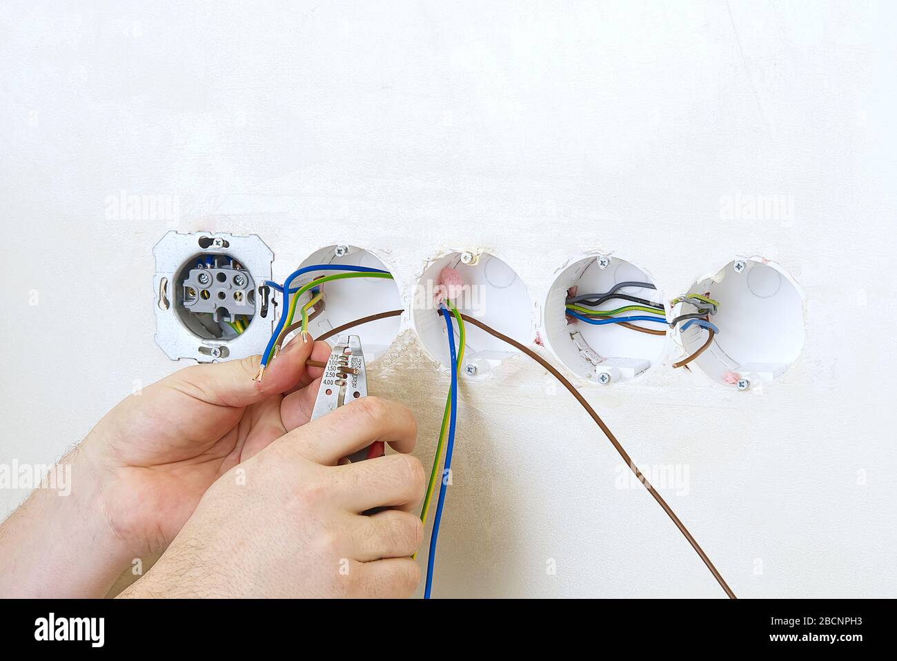 Electrician install outlets on beige wall with eu standards Stock Photo