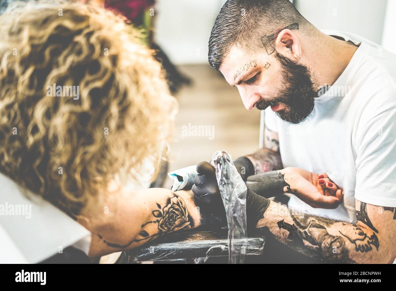 Young tattoo artist working in his ink creative studio - Tattoist at work -  Contemporary skin trends - Focus on his head Stock Photo - Alamy