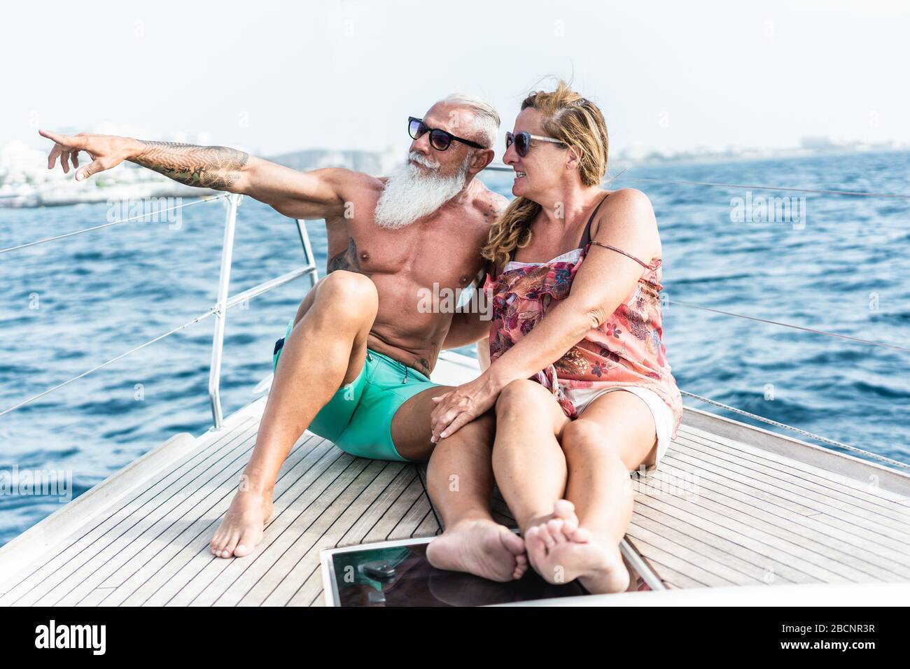 Senior couple on sailboat during luxury ocean trip vacation - Old trendy people having fun on exclusive holiday - Travel and joyful elderly concept - Stock Photo