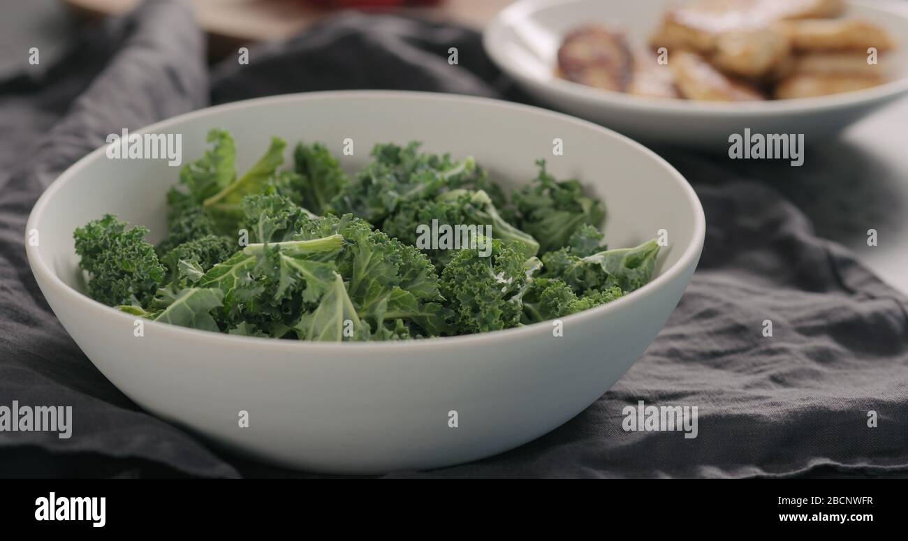 kale leaves in white bowl on countertop Stock Photo