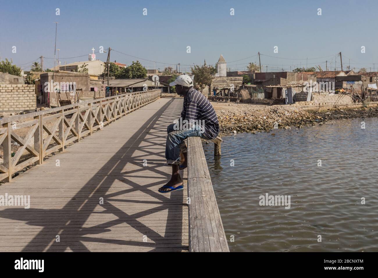 Local man is sitting is sitting on the bridge in Joal-Fadiouth, Senegal Stock Photo