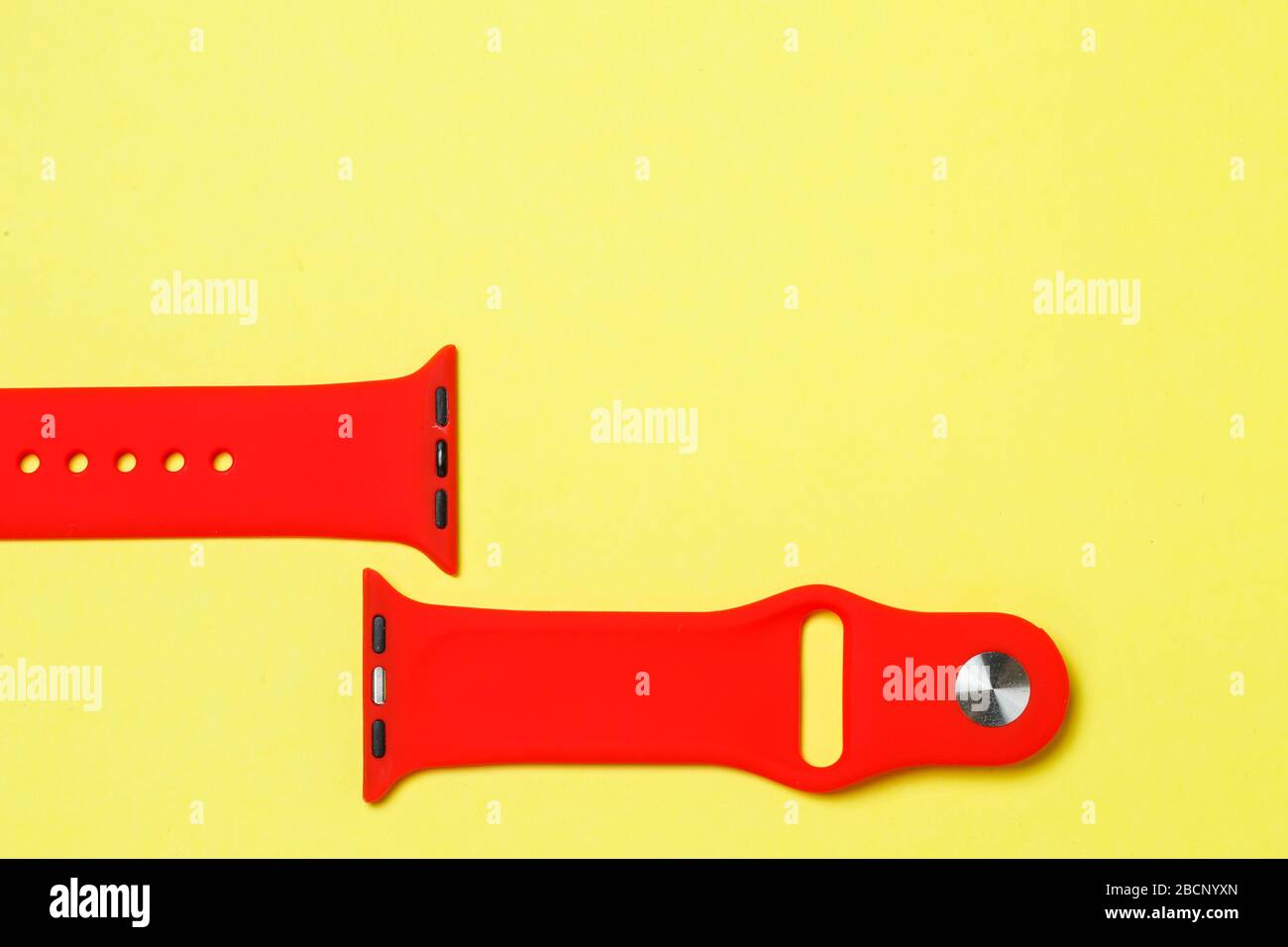 silikone strap for smart watch red color on yelow background Stock Photo