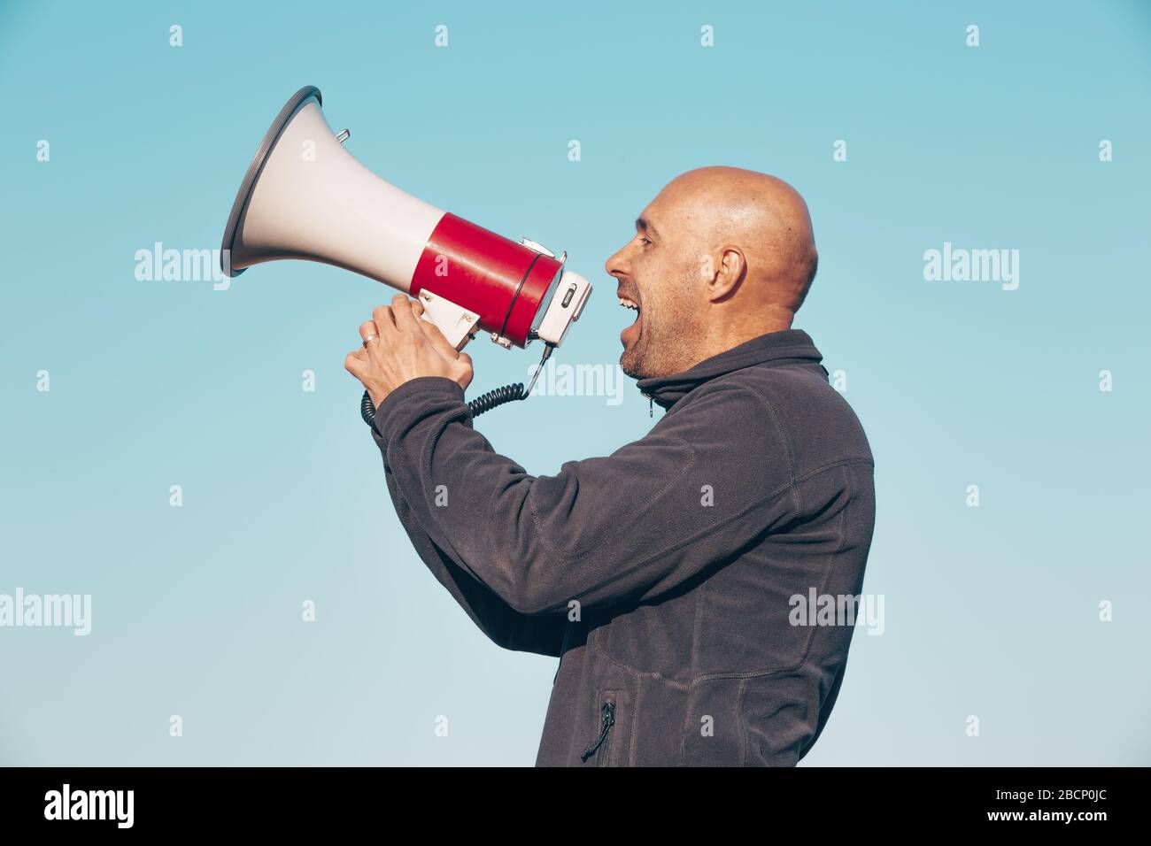 Cheerful man shouting, screaming through a megaphone, announcing something news8 Stock Photo