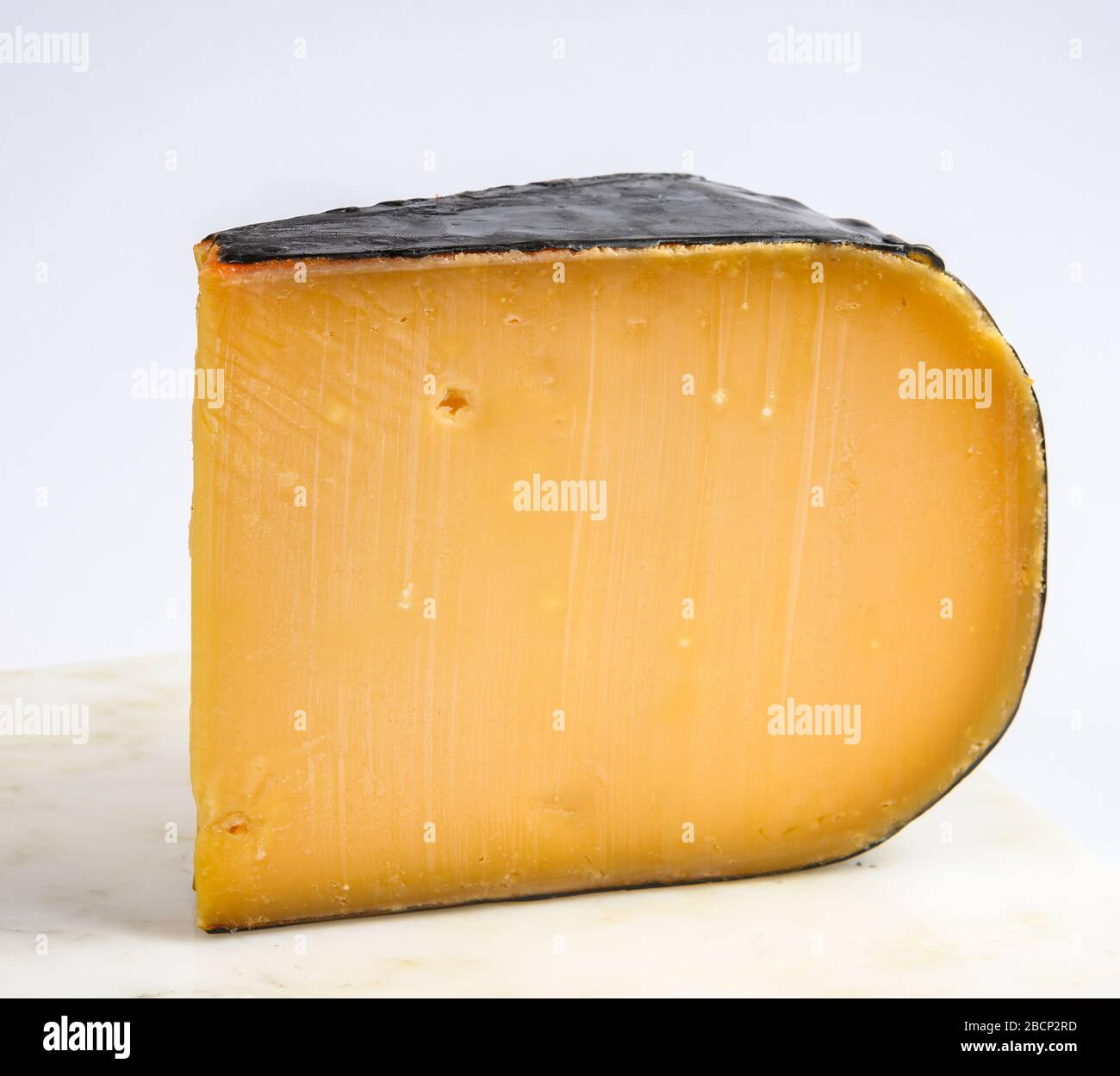 One piece of old Dutch gouda cheese with black wax close up Stock Photo