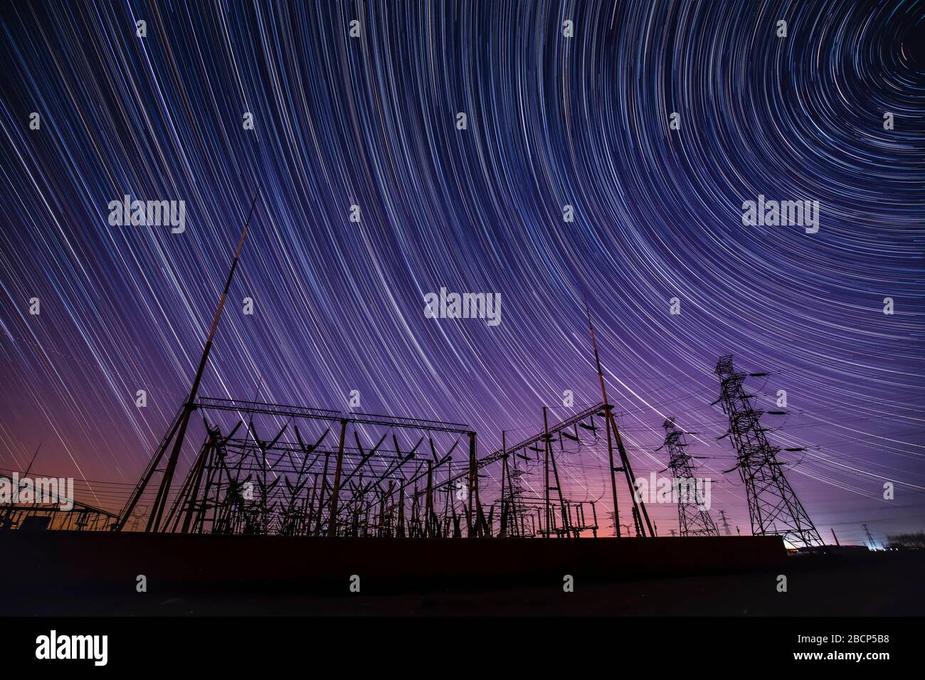 High-voltage towers and star trails at night Stock Photo