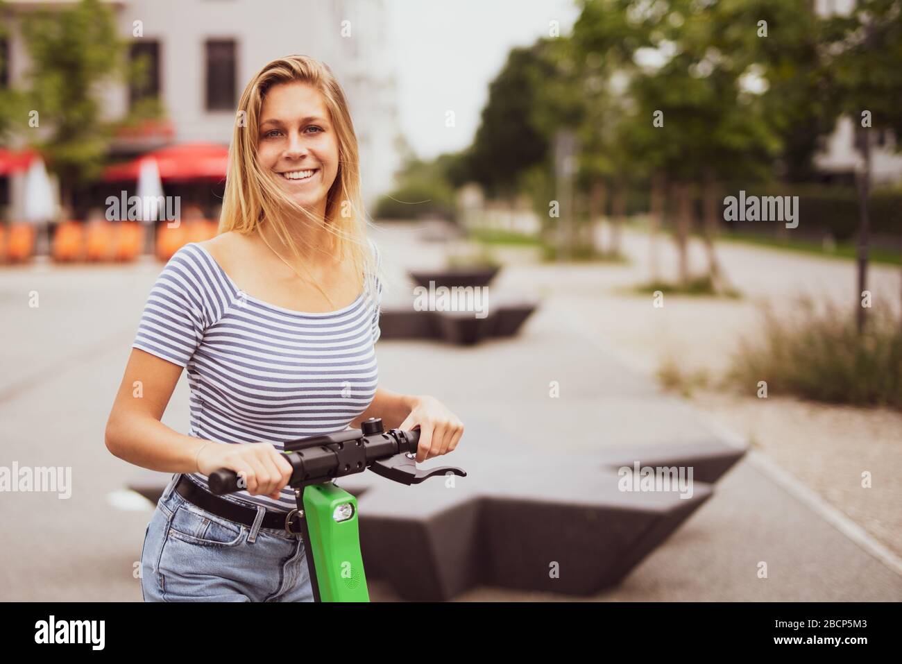 Pretty young woman is traveling in the city with an electric scooter Stock Photo