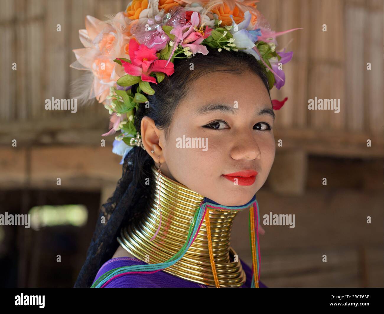 Pretty Thai/Burmese long-neck Kayan teenage girl (“giraffe woman”) with tribal Padaung brass neck rings/coils poses for the camera. Stock Photo