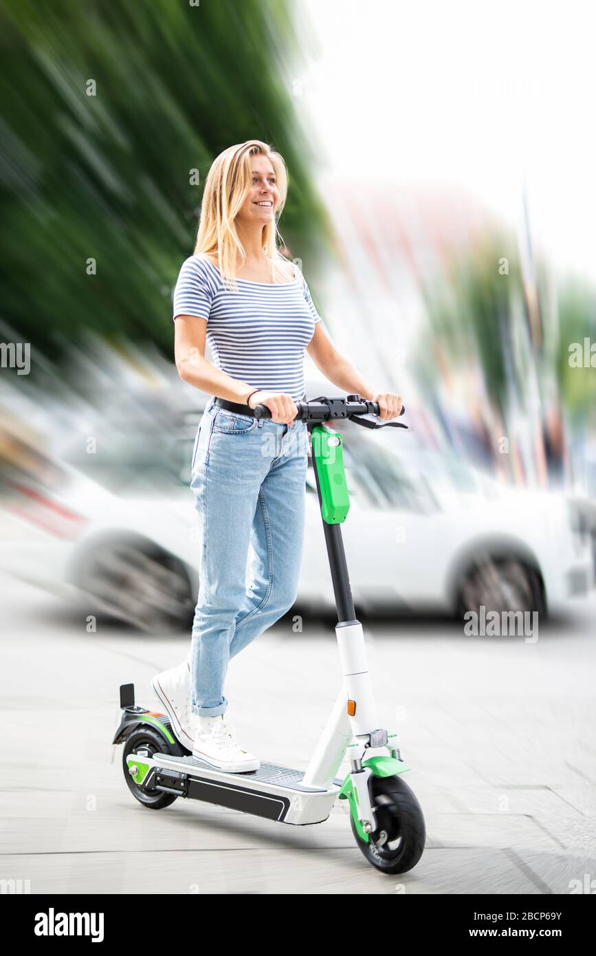 Pretty young woman is traveling in the city with an electric scooter Stock Photo