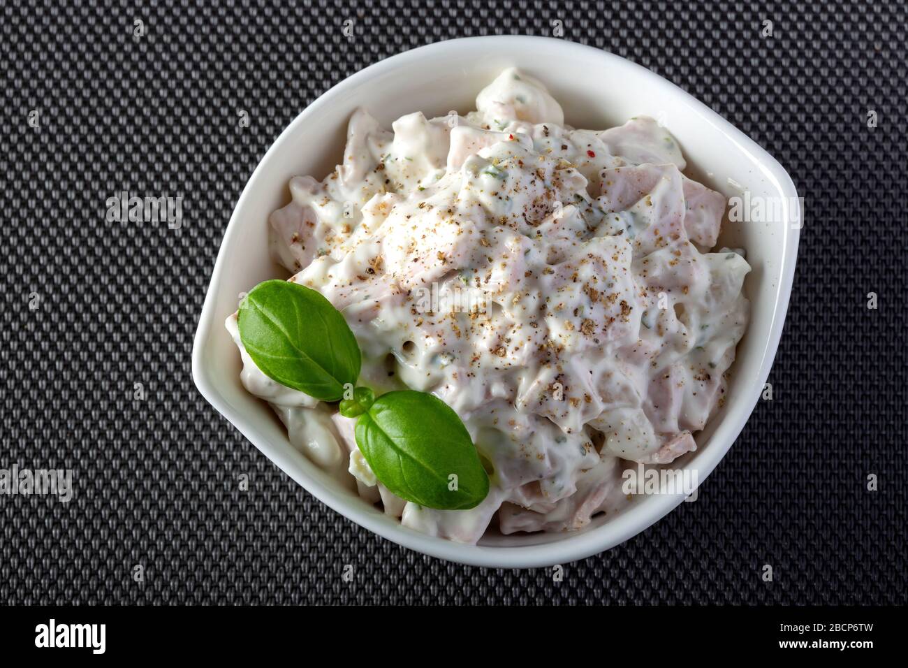 Meat salad with mayonnaise and herbs in a white bowl - top view Stock Photo