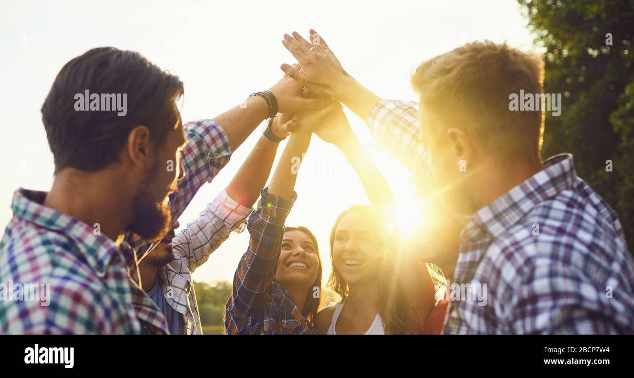 Group of young people join hands up outdoors. Stock Photo
