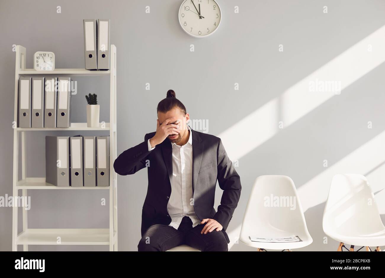 Unemployment. Crisis. Unemployed man in gray office. Stock Photo