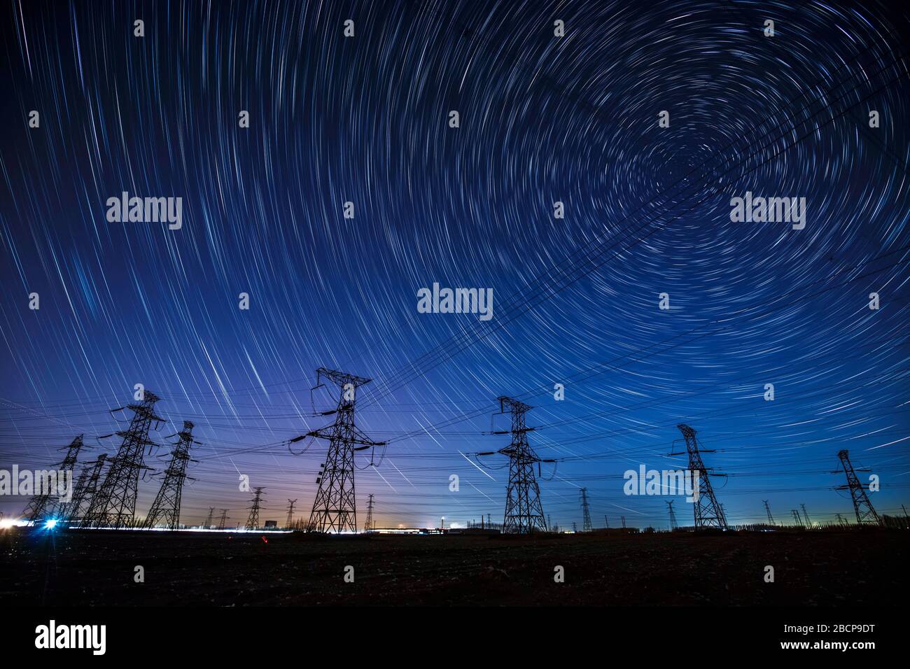 High-voltage towers and star trails at night Stock Photo