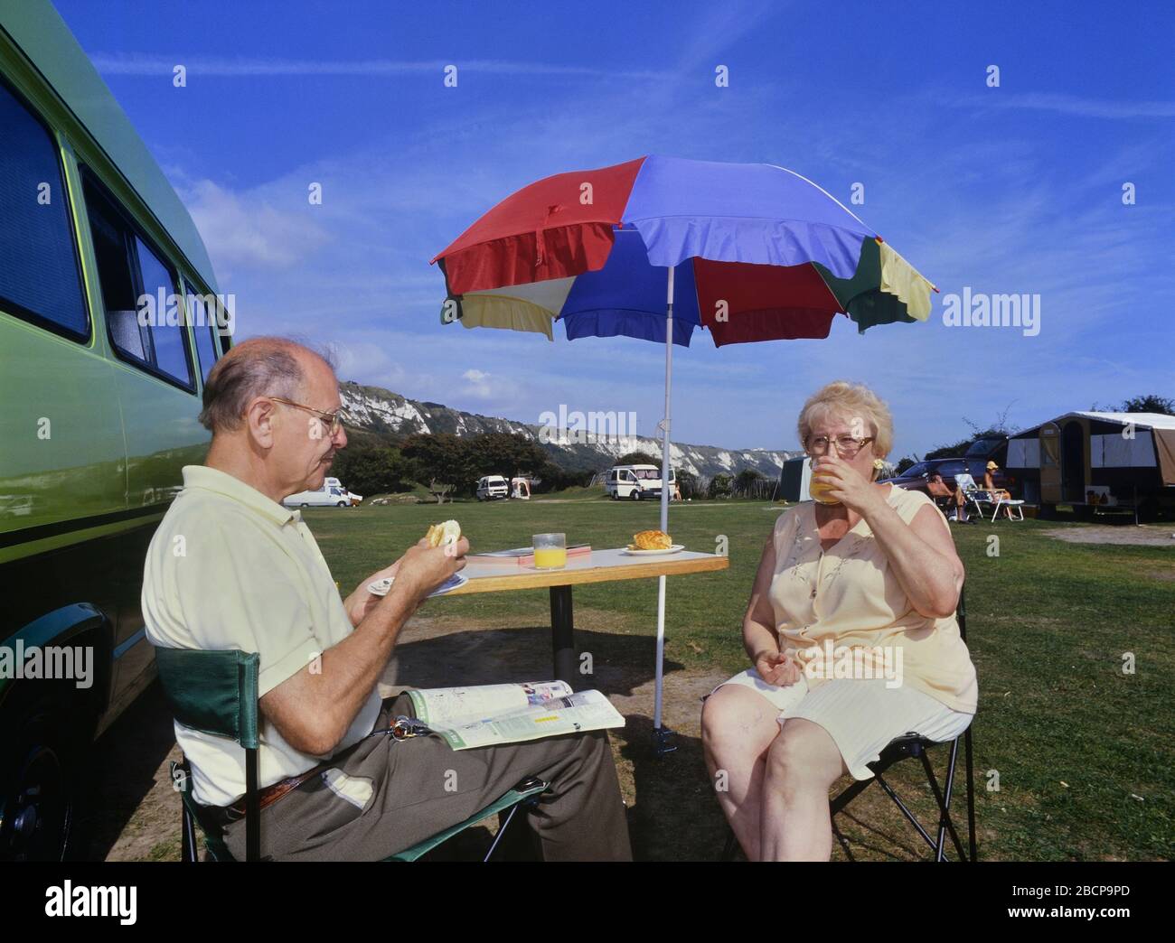 Elderly couple sitting outside their motorhome, Folkestone Camping & Caravanning Club Site, Kent, England, UK Stock Photo