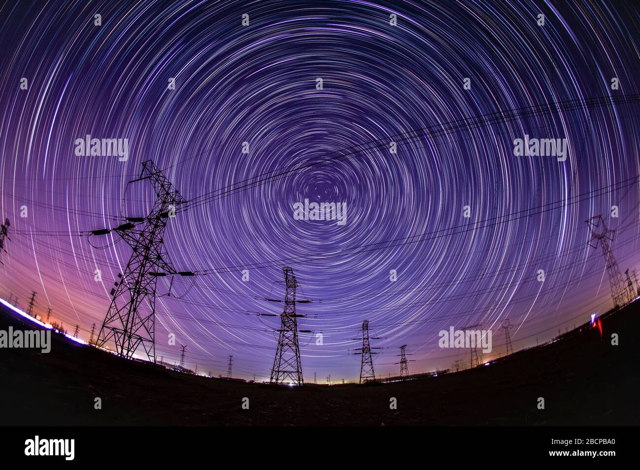 High-voltage towers and star trails at night Stock Photo