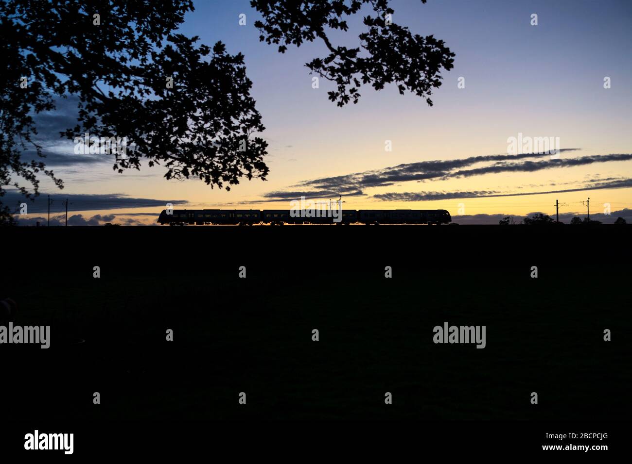 Northern Rail / Northern Trains CAF Civity class 195 train on the west coast mainline at sunset making a silhouette. Stock Photo