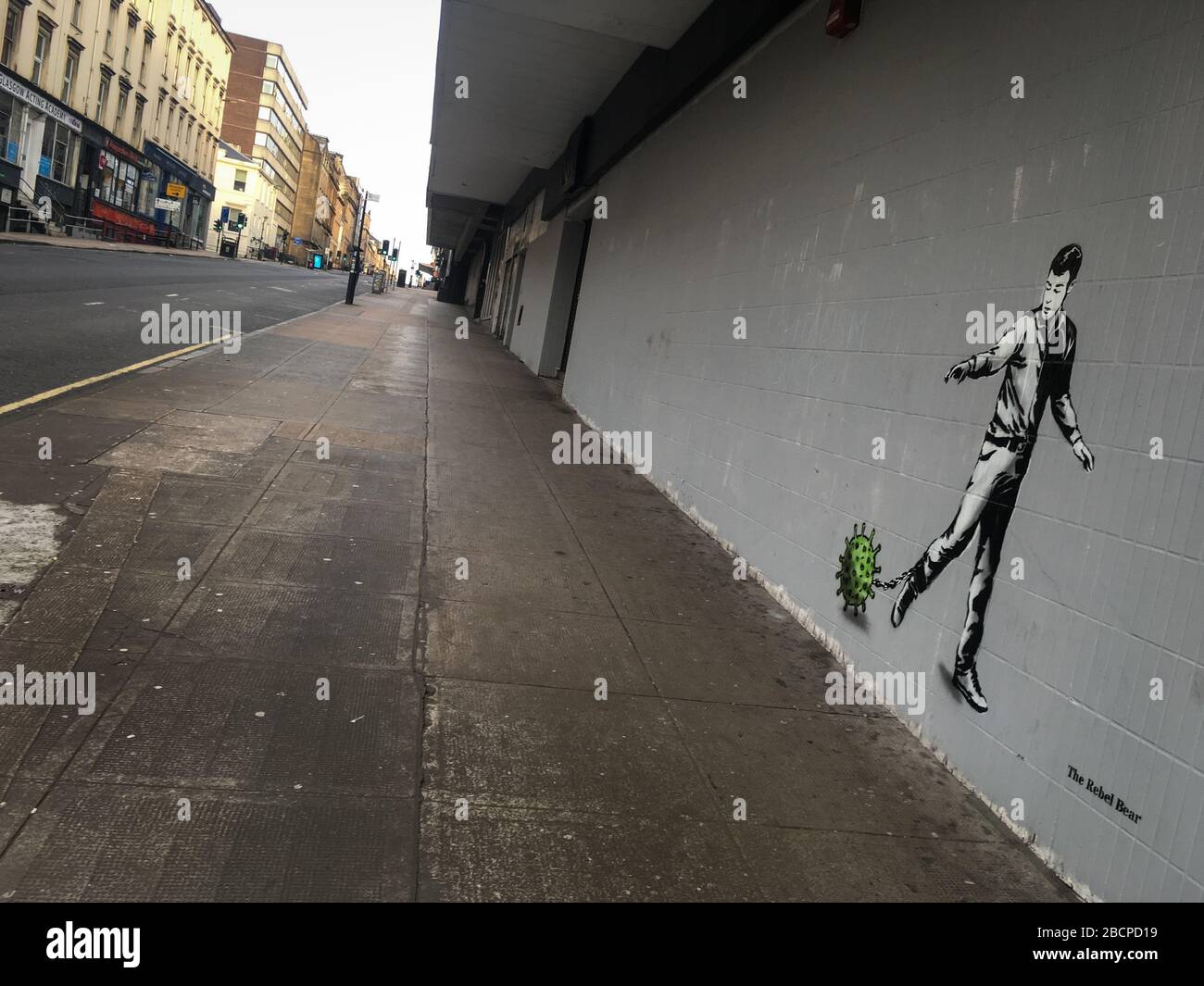 Glasgow, UK. 5th Apr, 2020. A new mural by the street artist The Rebel Bear depicting a man chained to a virus molecule, in empty streets in the city centre, illustrating that social distancing guidelines and 'stay at home' advisories are being adhered to in the time of Coronavirus COVID-19 pandemic crisis. Photo Credit: jeremy sutton-hibbert/Alamy Live News Stock Photo