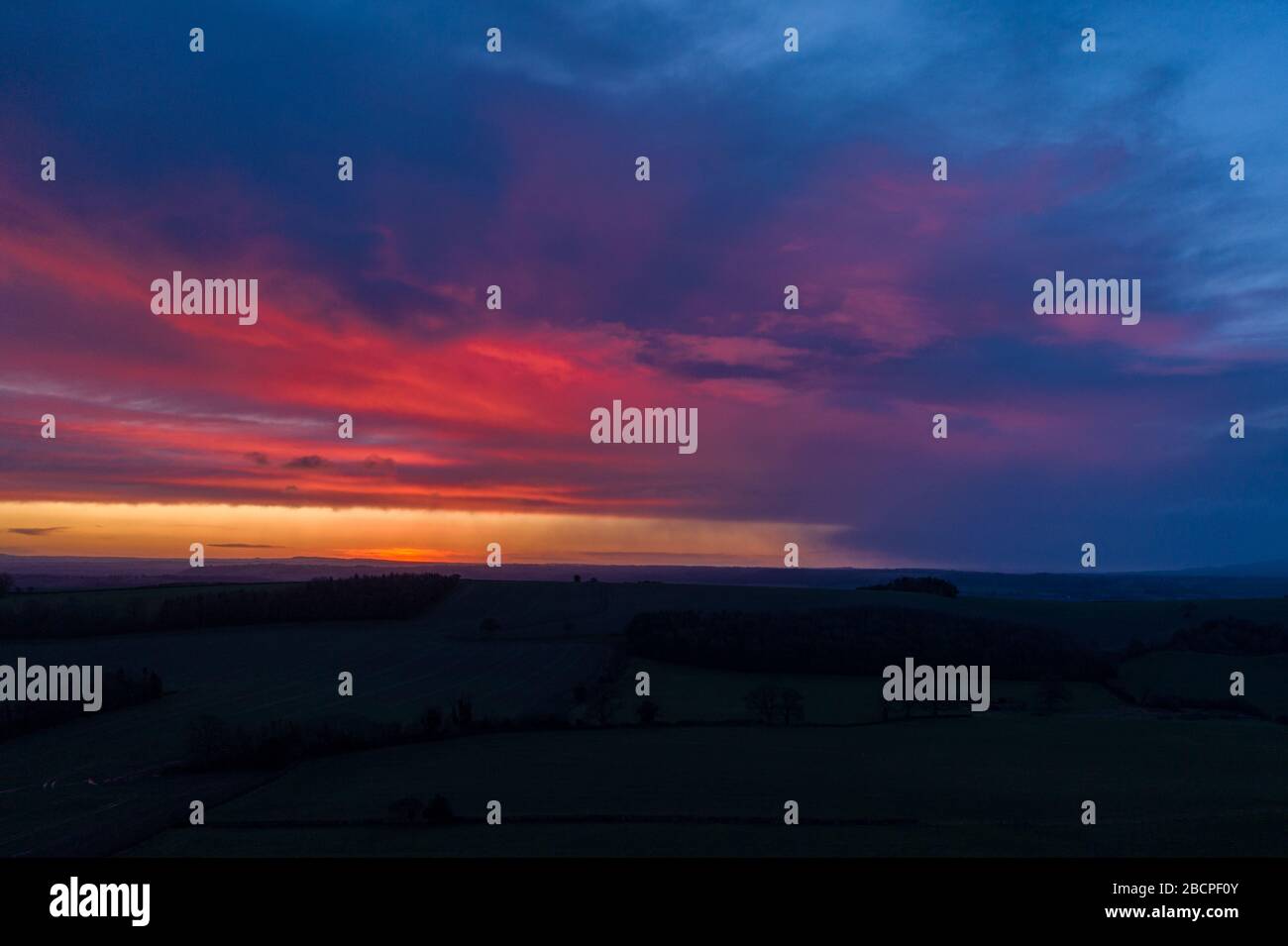 Dramatic colourful clouds over farming fields at dawn - aerial view. Shropshire Hills in United Kingdom Stock Photo