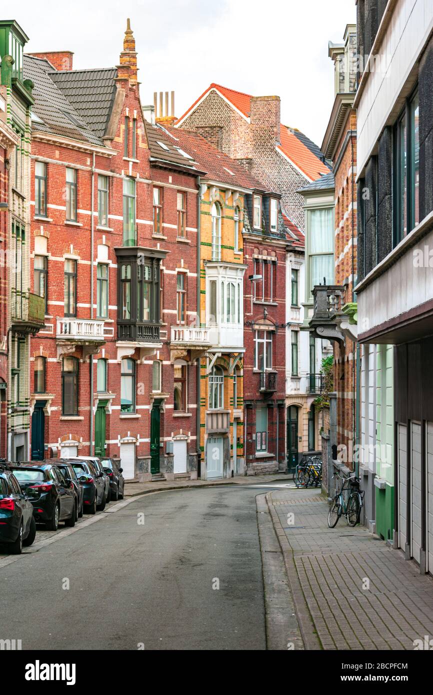 A street without people, with cars and bicycles. Colourful brick
