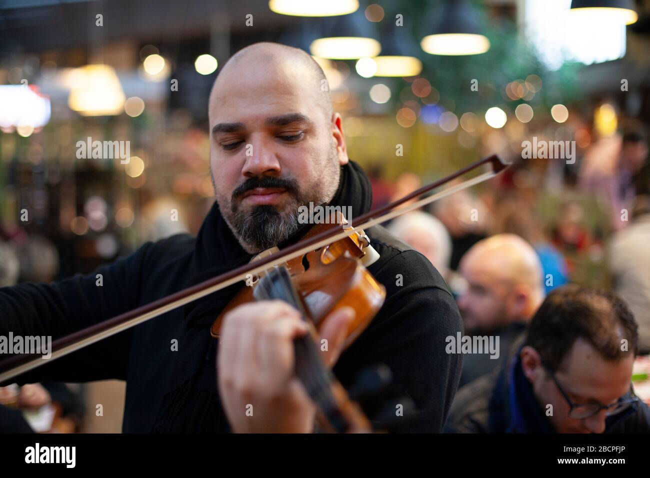 A fiddler plays to a restaurant audience in the Central Market Hall, Budapest, Hungary in winter Stock Photo