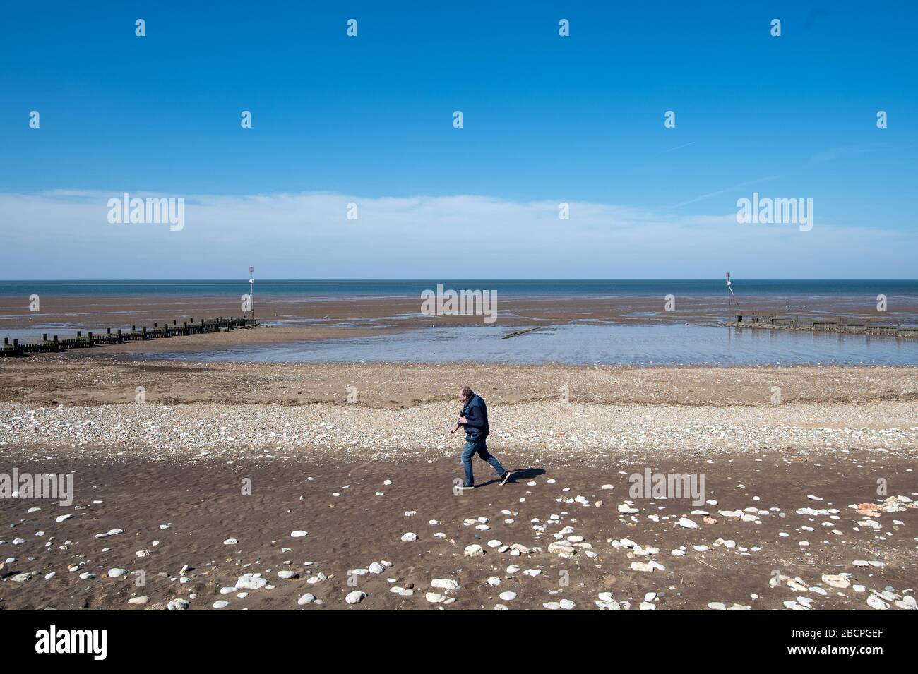 A man walks along a deserted Hunstanton beach in Norfolk, as the UK continues in lockdown to help curb the spread of the coronavirus. Stock Photo