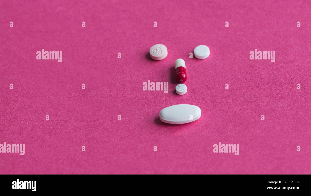 Five different heart tablets placed on a red background in the shape of a face. Stock Photo