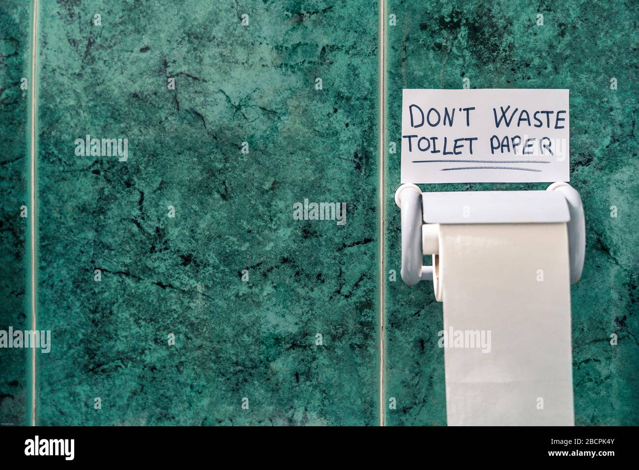 Don't waste toilet paper. Message on top of a toilet paper roll with space for text. Stock Photo