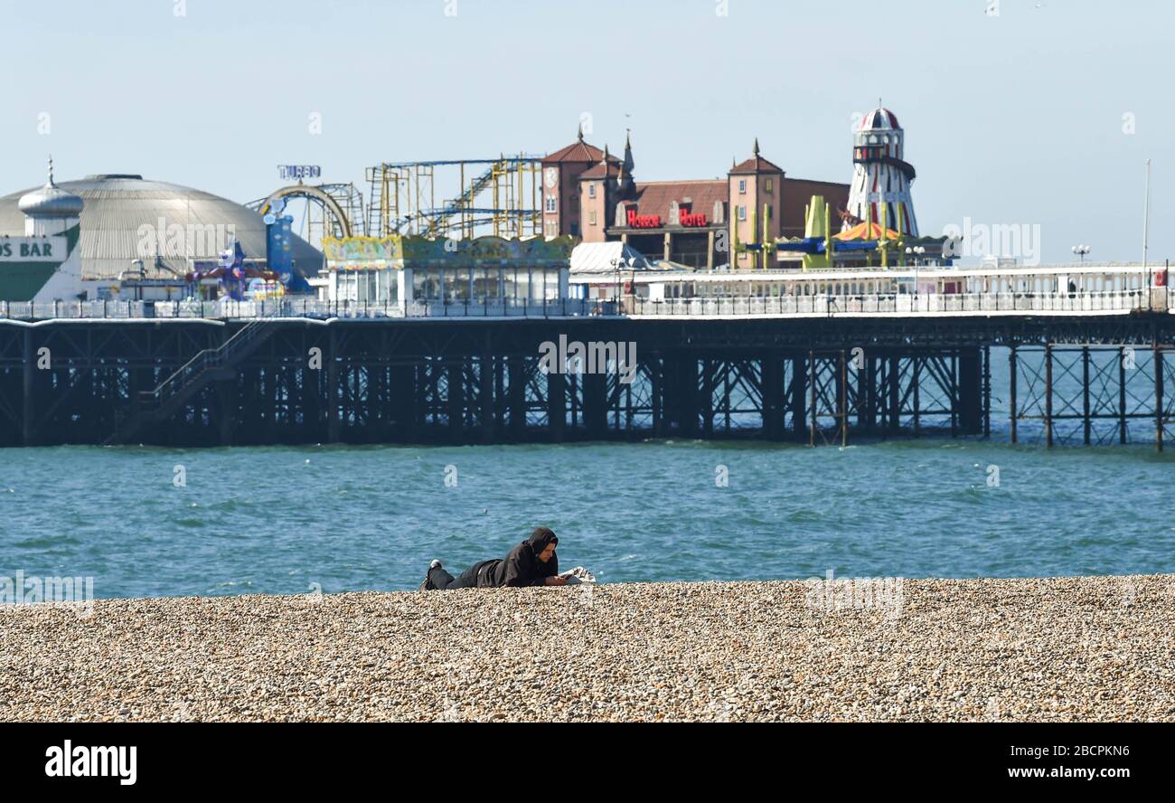 Brighton UK 5th April 2020 - A man lies on Brighton beach on a warm sunny day with temperatures expected to reach twenty degrees in London during the Coronavirus COVID-19 pandemic crisis . Health Secretary Matt Hancock has said today that they might have to revue the rules on exercising as too many people are ignoring the guidelines . Credit: Simon Dack / Alamy Live News Stock Photo