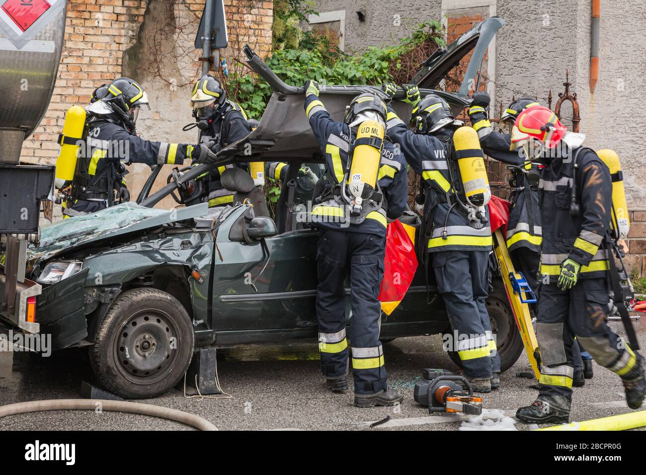 firefighters crewss rescue trapped driver during a road accident simulation with cars, train and trucks. firefighters with Breathing Apparatus and Hyd Stock Photo