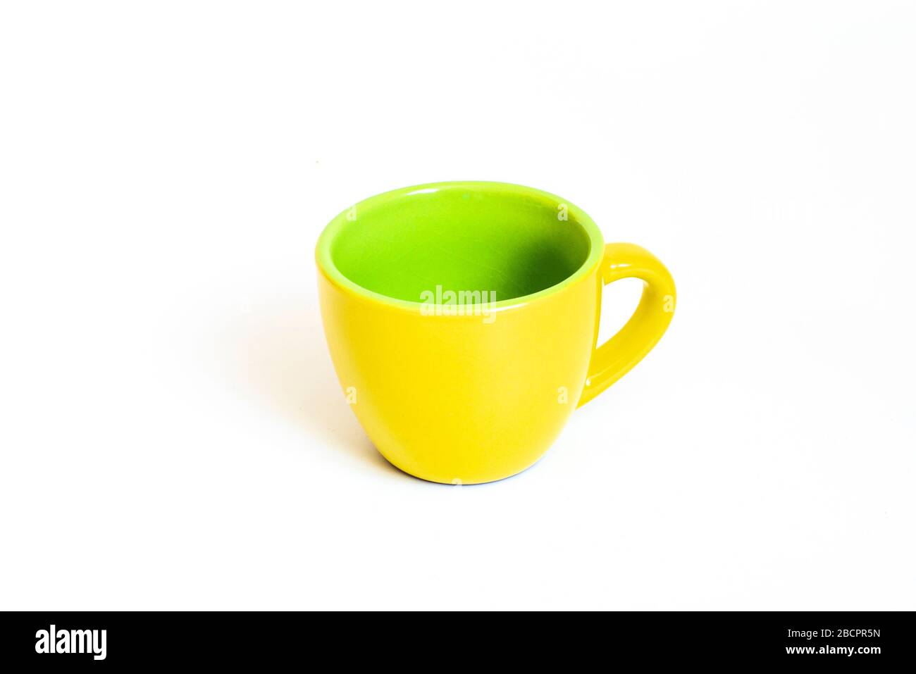 Little empty ceramic yellow and green coffee mug , coffee cup isolated on white background Stock Photo